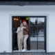 Elderly couple standing in front of prefab home holding coffee cups