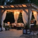 A gazebo at night time with soft lighting and curtains